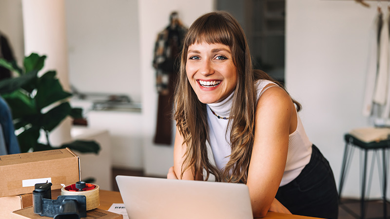 Woman smiling in her studio while she is using her notebook